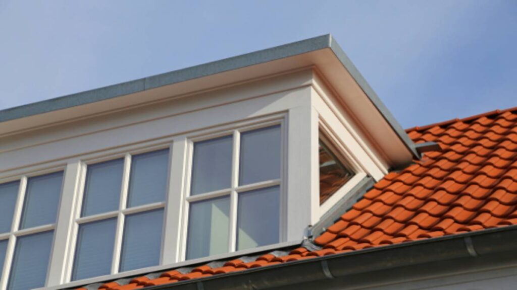 Een dakkapel van kunststof op een huis met oranje dakpannen.