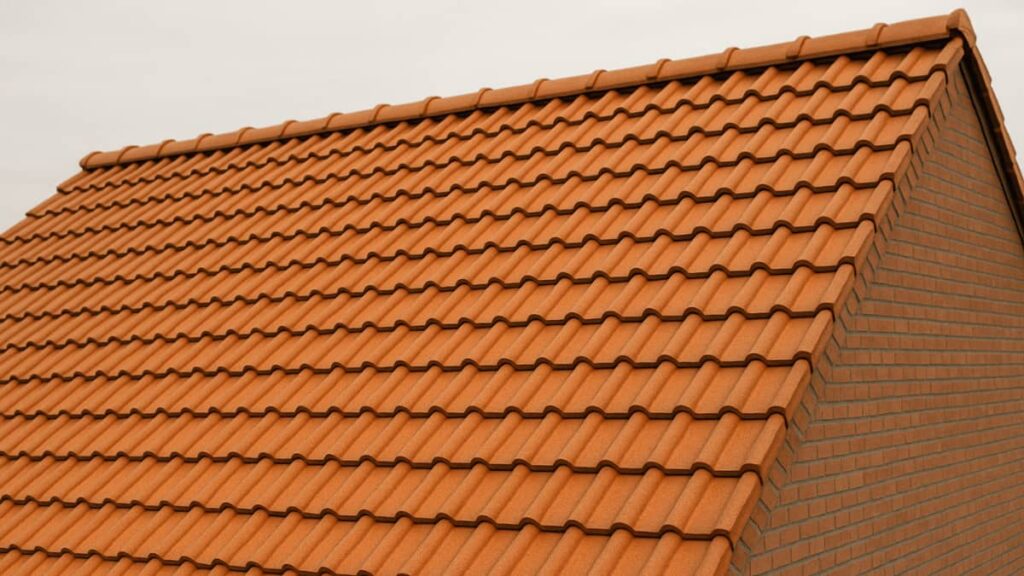 Close-up van een schuin dak in België met oranje gegolfde tegelpannen, inclusief nokpannen bovenaan en een bakstenen gevel aan de zijkant.