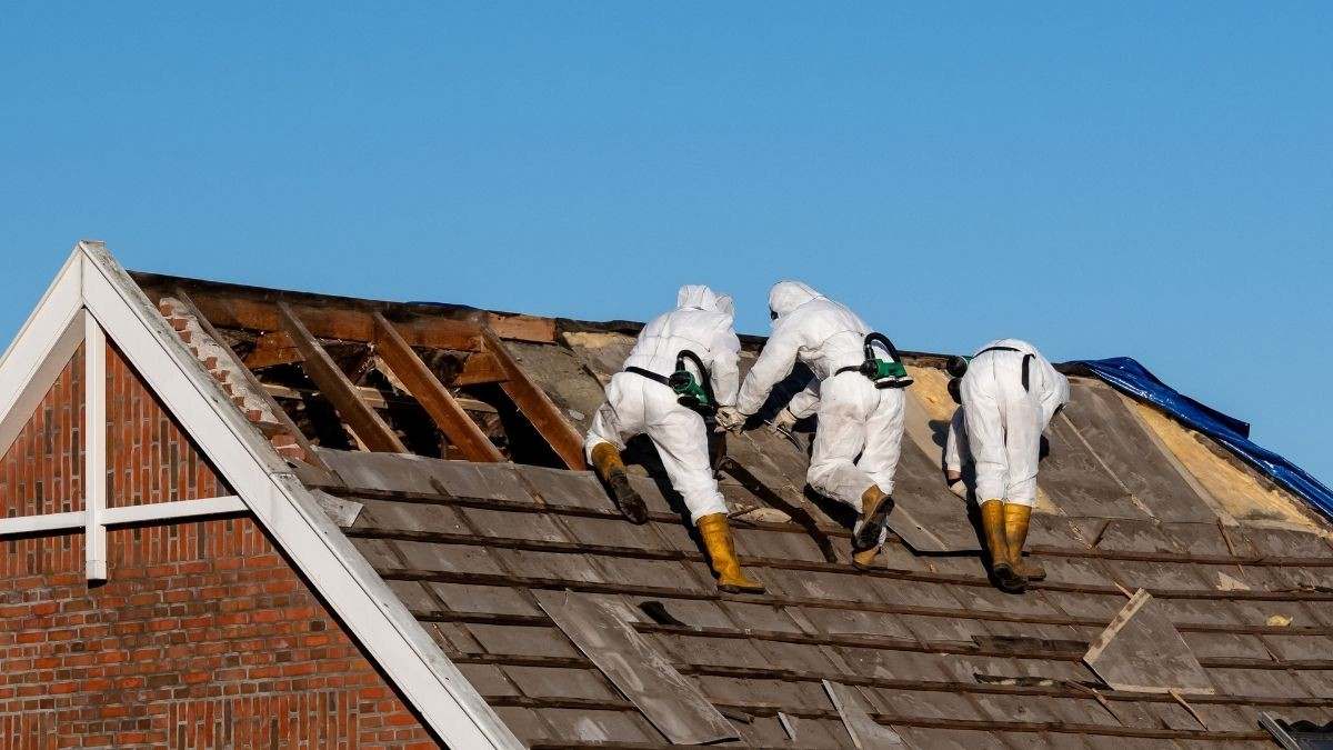 Specialisten met ademhalingsbescherming verwijderen asbestleien van een dak na het herkennen van asbest dakbedekking