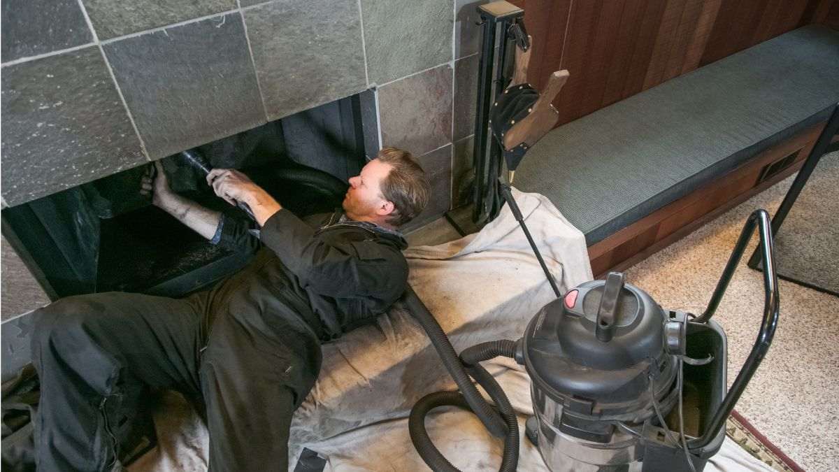 Schoorsteenveger reinigt een open haard van binnenuit, de prijs hangt af van de vervuilingsgraad