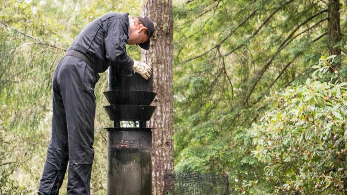 Schoorsteenveger op het dak bij de reiniging van een schoorsteen, de prijs varieert per bereikbaarheid