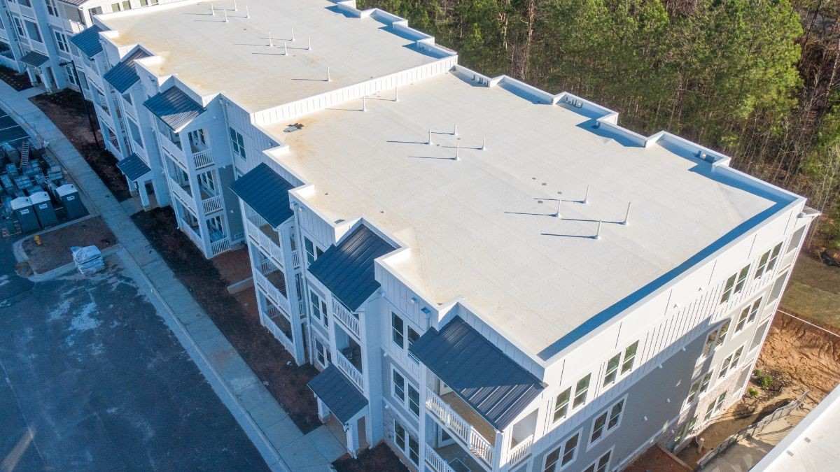 Bovenaanzicht van een appartementsgebouw met witte tpo dakbedekking op de platte daken en blauwe gevelelementen