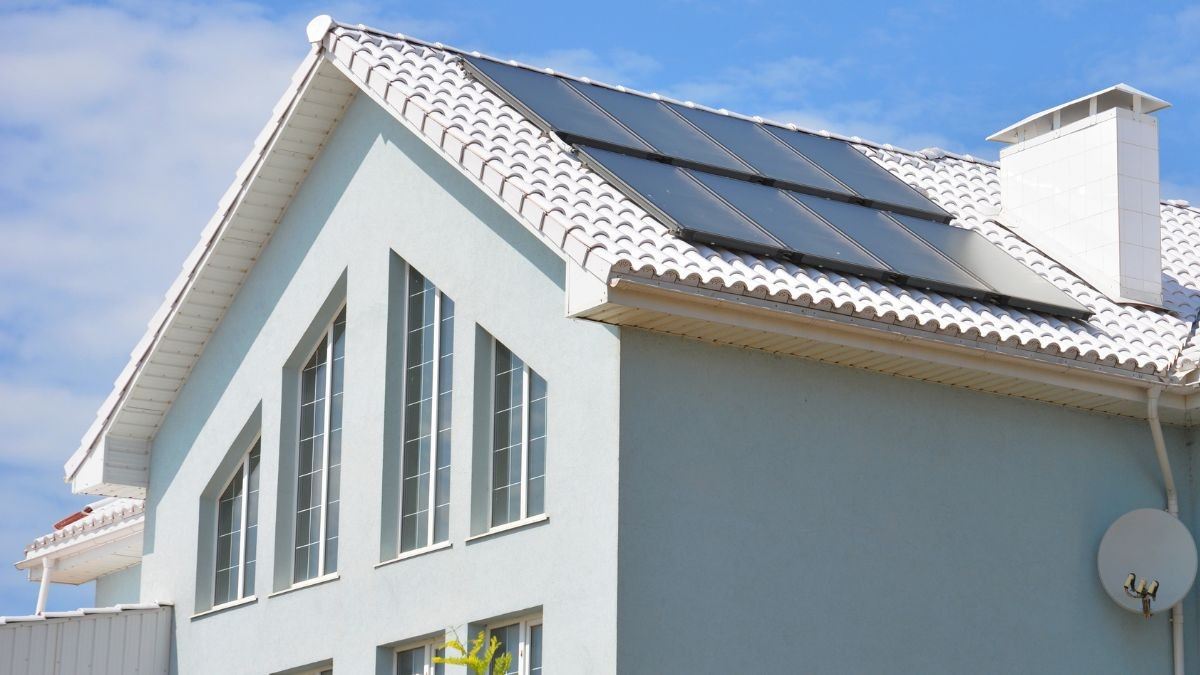 Woning met wit geverfde dakpannen en zonnepanelen op het dak die het zonlicht reflecteren en de woning koeler houden