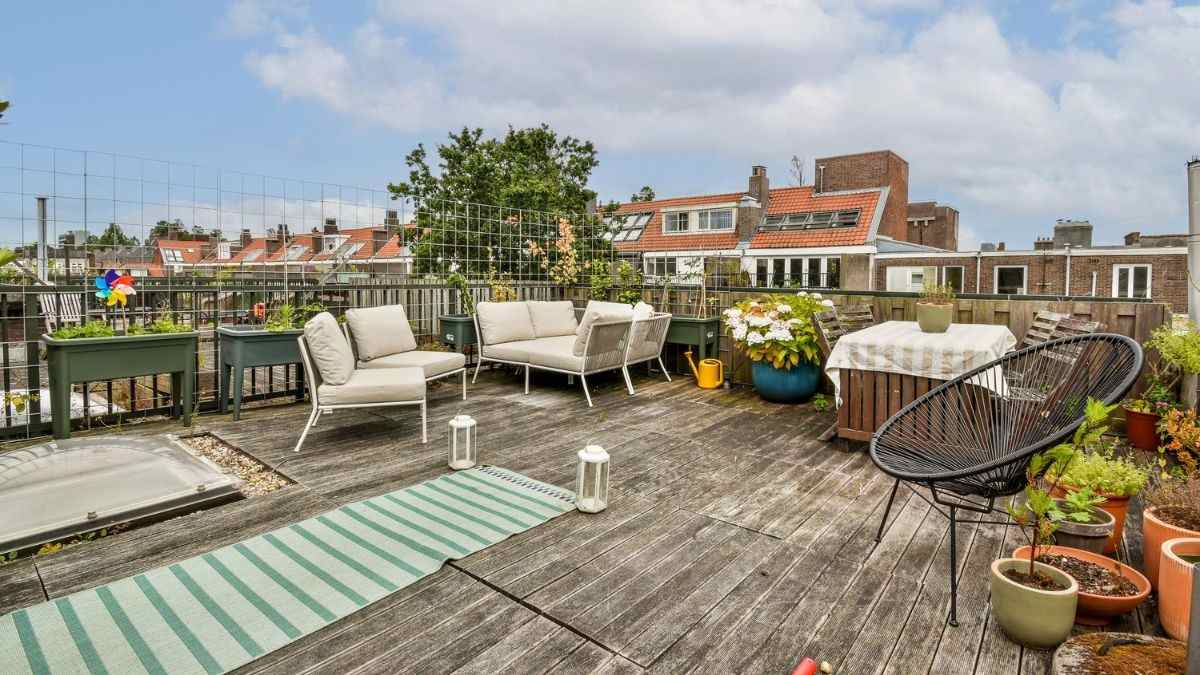 Gezellig ingericht terras met een loungehoek, lantaarns en plantenbakken op een verweerde houten vlonder