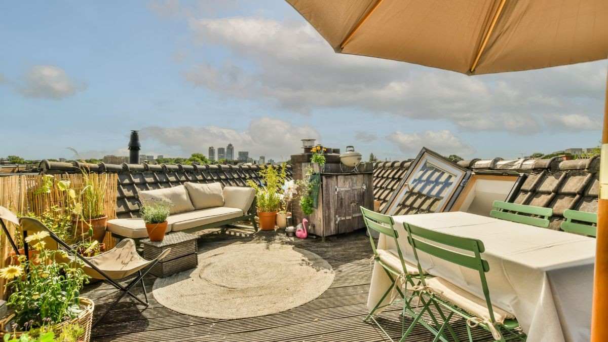 Gezellige eethoek met parasol op een houten dakterras aangelegd met uitzicht over de stadshorizon bij zonnig weer