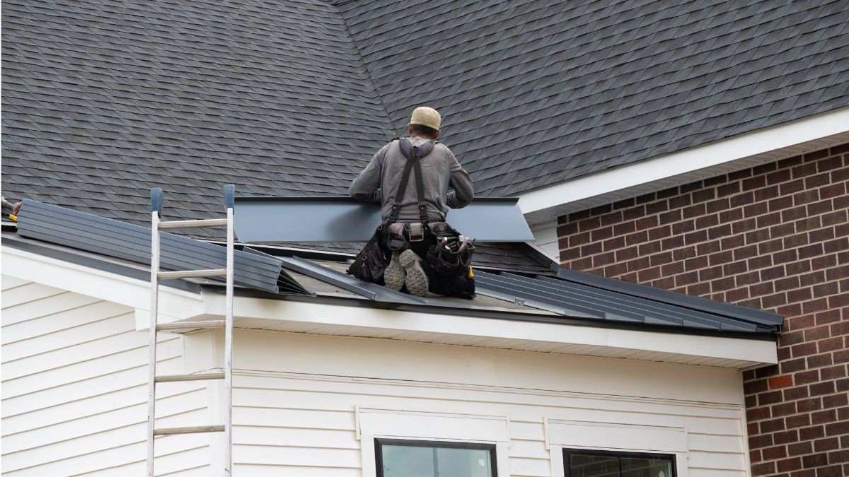 Een vakman monteert zinken platen aan de dakrand van een woning als onderdeel van het detailwerk aan de dakconstructie