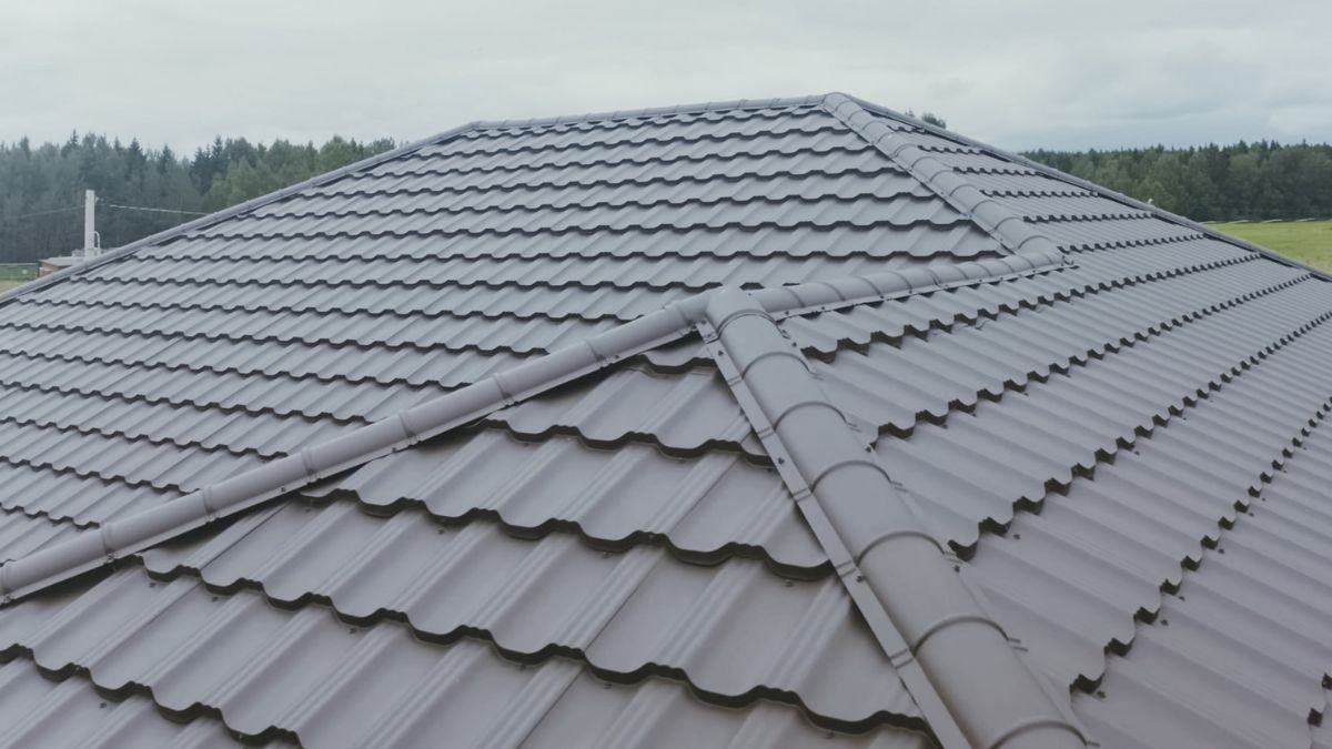 Close-up van een dakconstructie met zichtbare nok en diagonale hoekkepers afgewerkt met grijze pannen