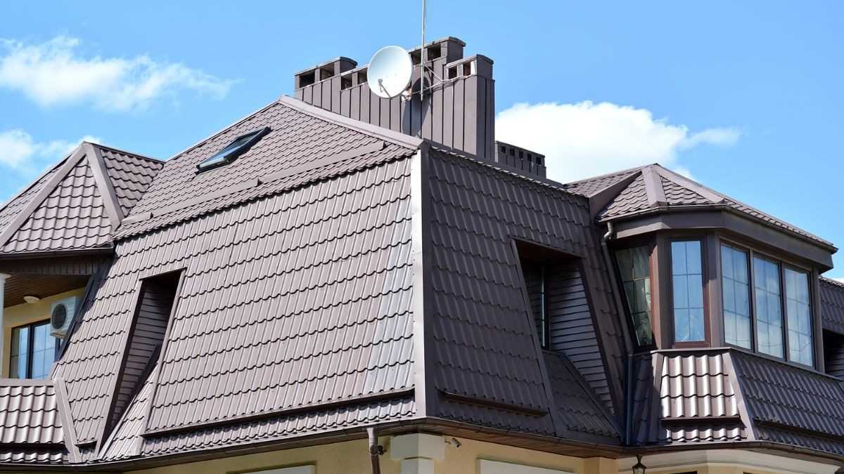 Ruime gebroken kap met bruine metalen dakpannen en meerdere dakkapellen op de steile onderste dakhelft
