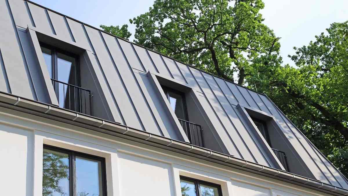 Moderne woning met een gepatineerd zinken felsdak en meerdere dakkapellen afgewerkt met de staande naadtechniek