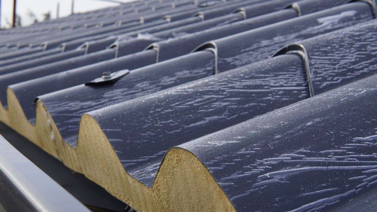 Close-up van geïnstalleerde dakpanelen met dakpanprofiel en zichtbare PIR-isolatiekern op een hellend dak