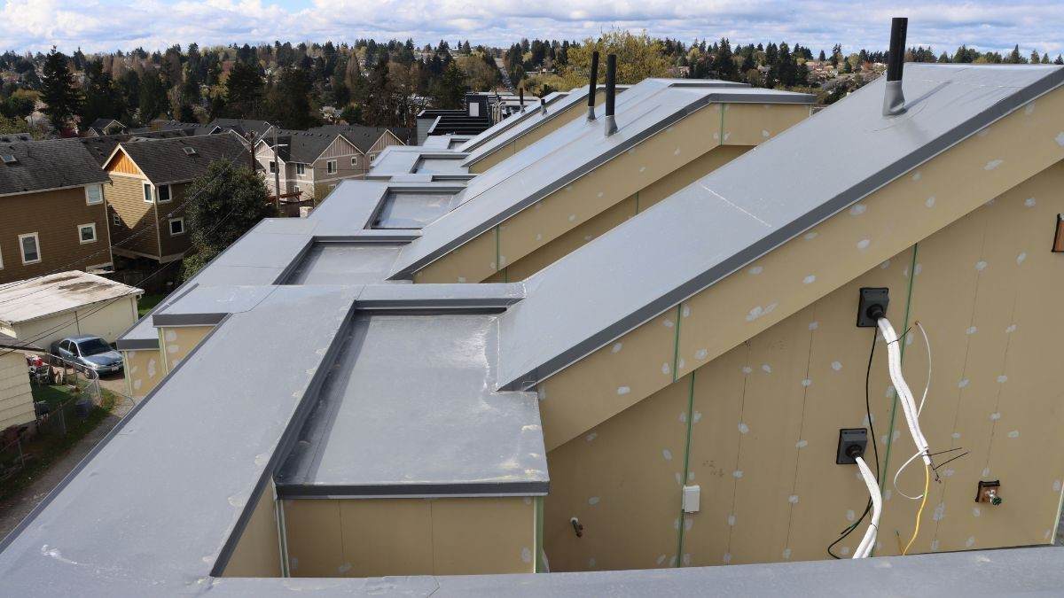 Detailopname van tpo folie met metalen daktrim rondom complexe dakvormen en opstanden op een gebouw in aanbouw