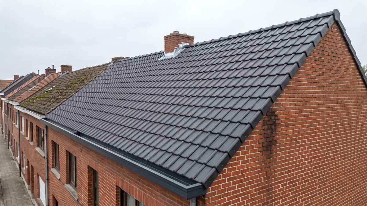 Pannendak van een Belgische rijwoning na dakrenovatie met nieuwe uniforme antraciet dakpannen en vernieuwde dakgoot