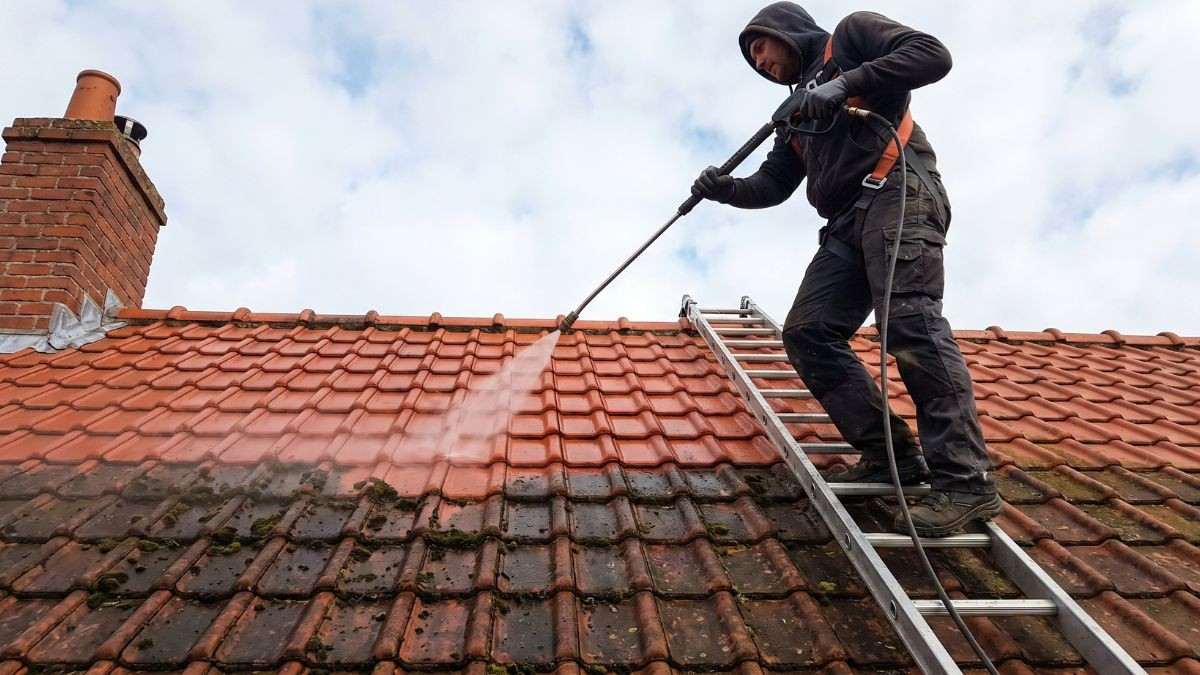 Bemoste rode dakpannen worden gereinigd met een hogedrukreiniger, een vaste voorbereiding voor dak coaten door een dakwerker