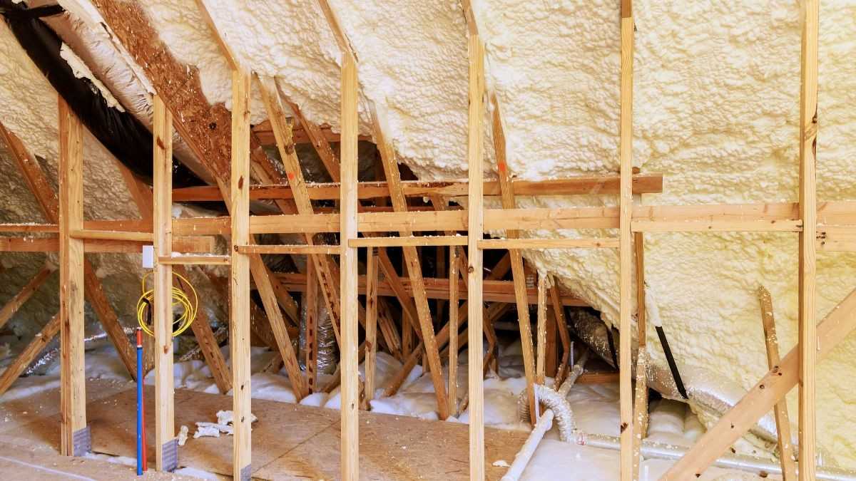 Gespoten schuim tussen de houten dakspanten van een zolder, waarbij de isolatie het volledige dakvlak naadloos afdekt