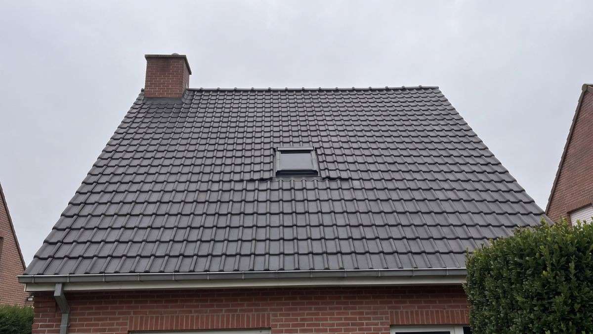Na het dak coaten heeft hetzelfde hellende pannendak met dakraam een egale antracietkleurige afwerking zonder mos of vlekken