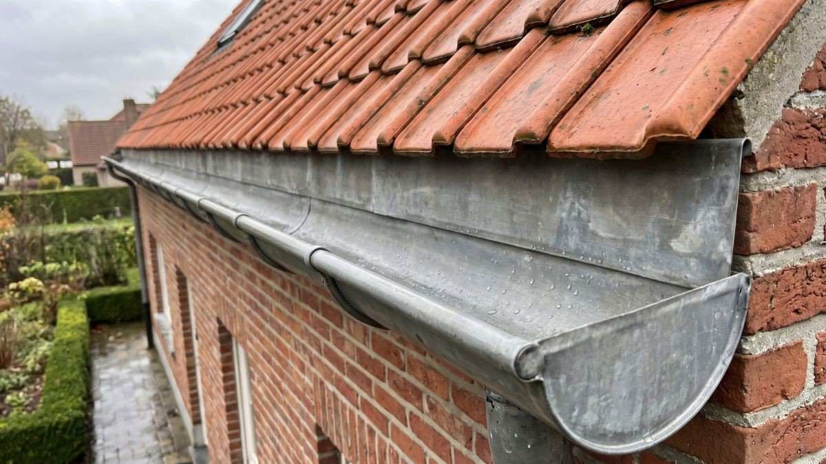 Propere zinken goot zonder bladeren of mos na een grondige reinigingsbeurt door een vakman bij een bakstenen woning
